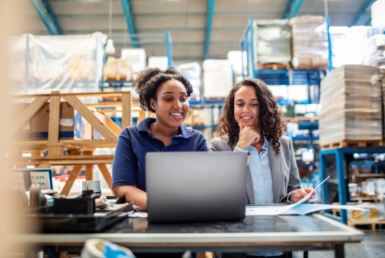 Frauen vor einem Laptop in einer Lagerhalle