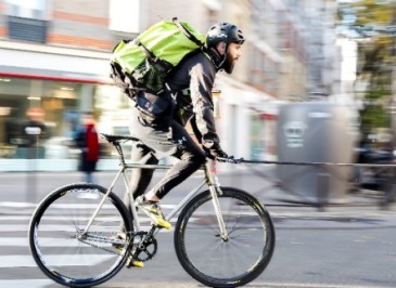 Livreur à vélo avec un sac de livraison, illustrant une solution de livraison durable pour le dernier kilomètre à Paris.