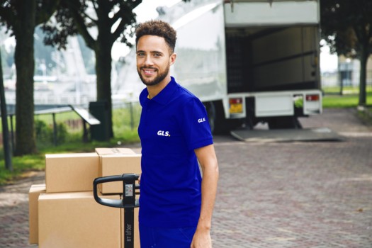 Witte GLS-vrachttrailers staan buiten een depot onder een heldere blauwe lucht.